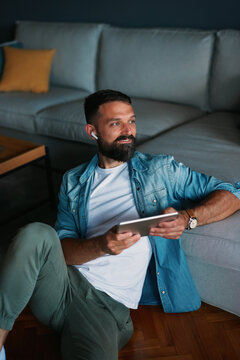 Man relaxing at home listening contemplating enjoying tablet