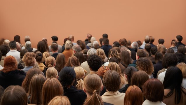 A large and diverse group of people gathered in a room, facing a blank wall, likely attending a conference, seminar, or lecture.