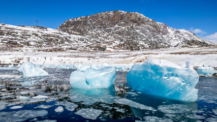 Turquoise iceberg fragments and sea ice in calm arctic water with mountain scenery near Narsaq, Kujalleq, Greenland © vadim.nefedov