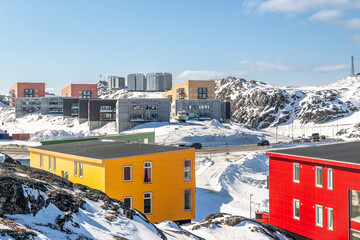 Modern colorful residential buildings on snowy rocky hills in Nuuk with arctic winter landscape, blue sky and urban Greenlandic architecture, Nuuk, Sermersooq, Greenland © vadim.nefedov