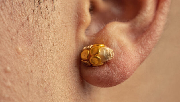 Close up of a luxury gold stud earring worn on a person earlobe
