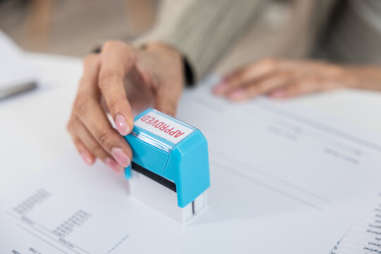 Approved stamp document hand office paperwork business. Close up hand holding stamp marking approved document desk, concept of authorization, verification, administration, and workflow efficiency