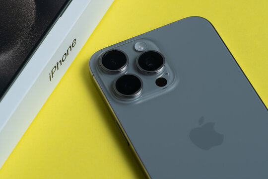 Kyiv, Ukraine - April 17, 2025: Apple iPhone 15 Pro Max unboxed with triple cameras on isolated yellow background, close-up view