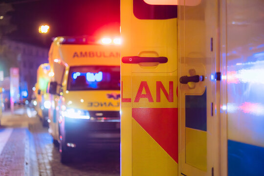 Selective focus on open rear doors of emergency ambulance in row on city street at night. Emergency medicine, paramedic response, patient transport, accident, and healthcare concept.