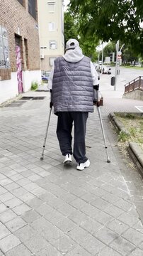 Se&ntilde;or con muletas tercera edad apoyo ortop&eacute;dico de movilidad reducida bast&oacute;n ingl&eacute;s , rehabilitaci&oacute;n muleta canadiense y recuperaci&oacute;n por la calle