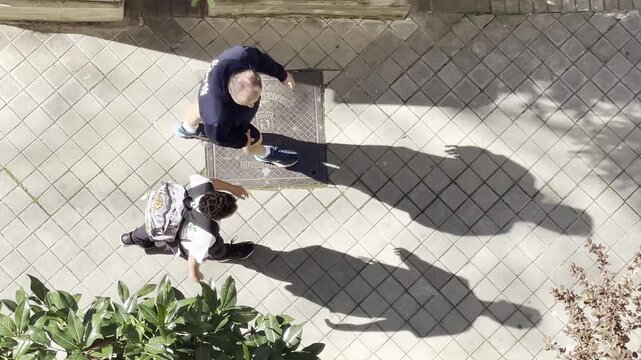 Padre e hijo sombra suelo abrazo, beso y cari&ntilde;o caminar en calle vuelta al cole con mochila cuidar acompa&ntilde;ar comprender aprendizaje infancia paternidad ni&ntilde;o peque&ntilde;o perspectiva a&eacute;rea desde arriba