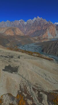 Aerial view of Gulmit and the Hunza River valley with jagged mountain peaks under a clear blue sky Hunza Nagar, Gilgit Baltistan, Pakistan.