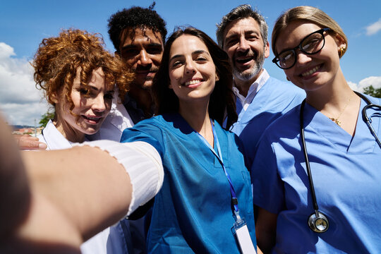 Diverse medical team taking happy selfie outdoors