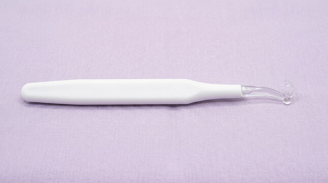 White droper with a clear plastic tip on a purple background for skincare or makeup use