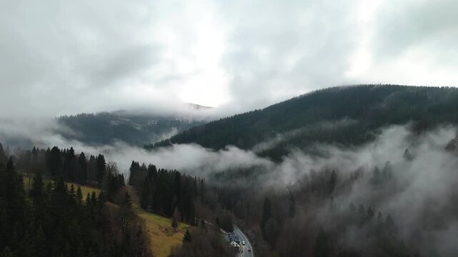 Aerial View of Misty Mountain Valley with Forested Hills, Road and Low Clouds Creating a Dramatic Landscape in the Krkonose Mountains, Czech Republic.