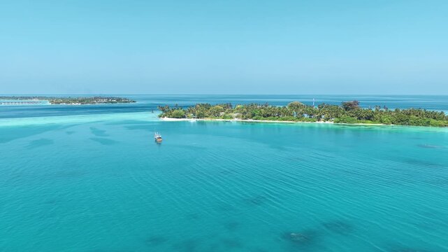Aerial view of a lush tropical island surrounded by crystal clear turquoise water and coral reefs in Kudahuvadhoo, Dhaalu Atoll, Maldives.