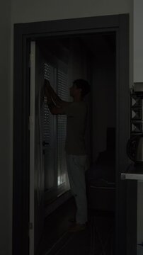 Mental health recovery and new beginning concept with young man opening blinds and window letting sunlight into dark apartment, emotional reset and fresh start, vertical video