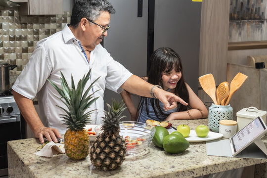 Grandfather and granddaughter cooking healthy food with tablet