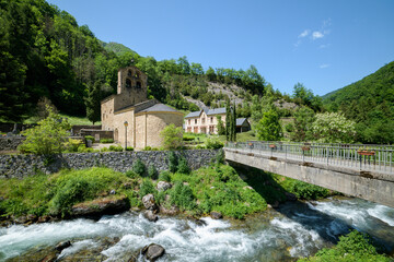 Fototapeta premium Mountain landscape with a 12th century Romanesque church and a river in the foreground. Salau Ariege Pyrenees France