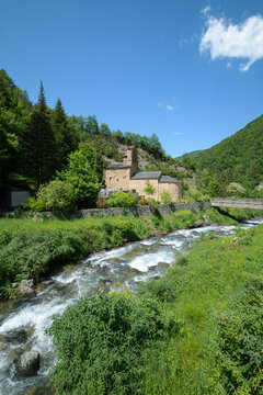 Mountain landscape with a 12th century Romanesque church and a river in the foreground. Salau Ariege Pyrenees France
