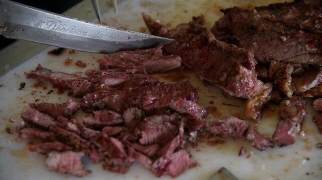 Beef barbecue being sliced ​​into pieces on a counter. Brazilian barbecue or brazilian bbq as known as brazilian barbecue
