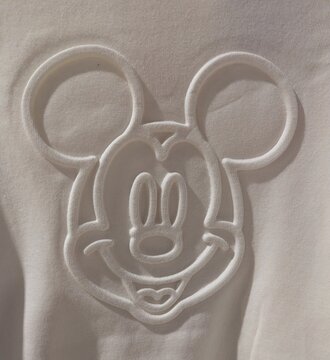 Vista de cerca de la cabeza de Mickey Mouse de Disney, en relieve termoformado o embossing textil, en una camiseta. Madrid, Espa&ntilde;a, 22 de abril de 2026