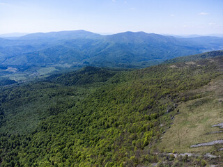 Fototapeta premium Mountain ridge under a clear blue sky with rocky alpine terrain and distant peaks. Scenic panoramic landscape of a rugged mountain range