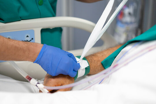 Healthcare worker restraining patient arm with medical device