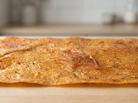A sheet of dried fruit leather roll-up on a wooden surface