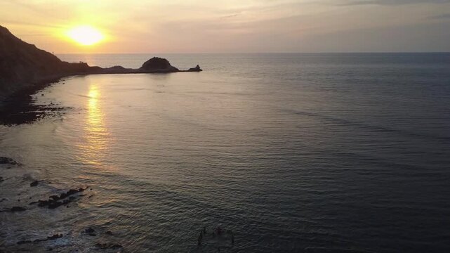 Aerial view of La Ti&ntilde;osa beach as the sun sets and some tourists enjoy the warm sea of ​​Manta, Ecuador, on the Pacific Ocean of South America with their families at the golden hour