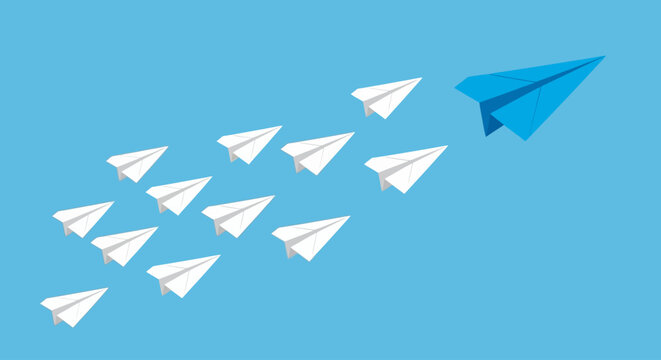 Blue paper airplane leads a flock of white paper airplanes in formation against a clear blue sky, symbolizing leadership and teamwork