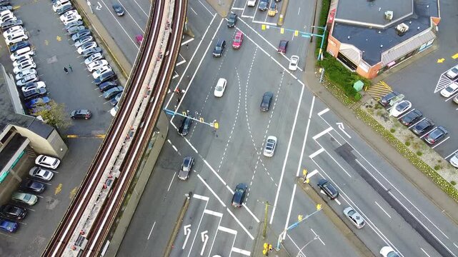 Drone shot of a busy city intersection, with a diamond shape as the cross streets are diagonal. Elevated rail track next to the intersection.