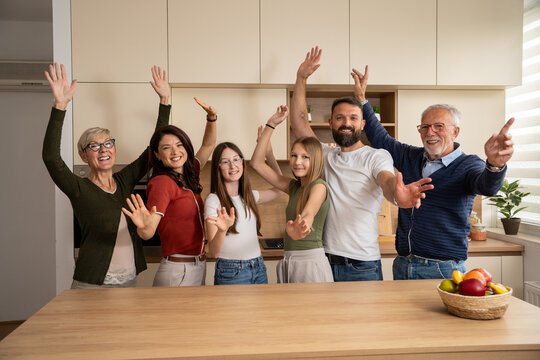 Multigeneration family smiling and waving together with happiness