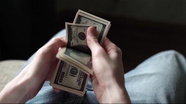 A man counts a stack of money, focusing on the bills in his hands. The scene highlights the man&rsquo;s fingers smoothly handling the cash repeatedly.