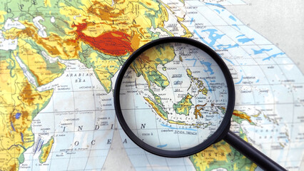 Magnifying glass highlighting Southeast Asia on a world map, symbolizing travel planning, regional analysis, tourism research, international business, and geographic exploration. © OrangRobot