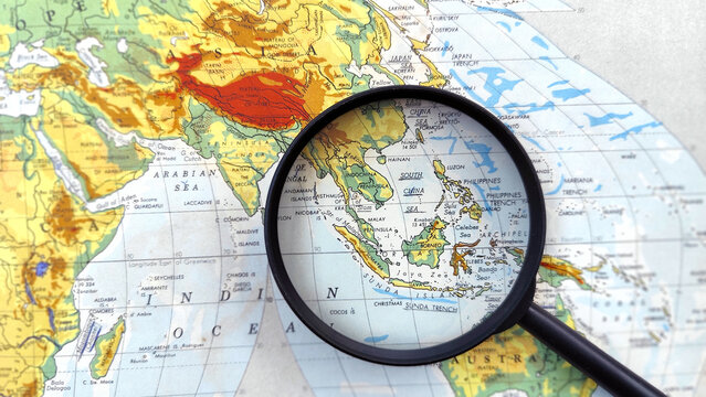 Magnifying glass highlighting Southeast Asia on a world map, symbolizing travel planning, regional analysis, tourism research, international business, and geographic exploration.