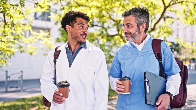 Two male doctors walking and talking on a coffee break outdoors