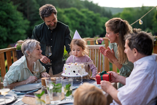 Little girl blowing candle from birthday cake.