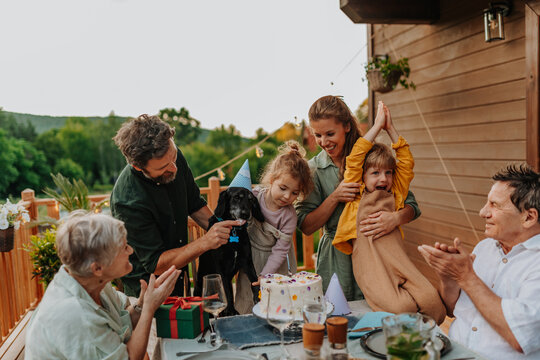 Multi generation family celebrating birthday and have garden party outside in the backyard on patio.