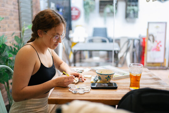 Young woman painting clay dog pottery craft hobby
