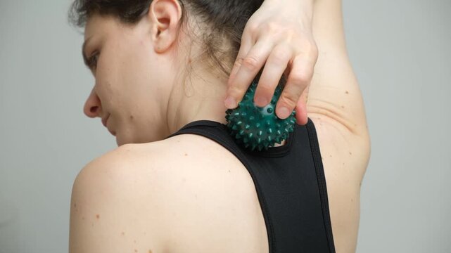 Woman Using Spiky Massage Ball for Neck and Upper Back Muscle Relief