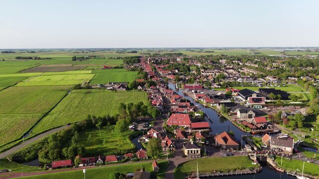 Aerial view of the historic town of Workum featuring red-roofed houses along a canal surrounded by lush green fields in Workum, Friesland, Netherlands.