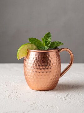 Served in its typical copper mug, a Moscow Mule combines vodka, spicy ginger beer, and lime juice, professional photography, neutral background.