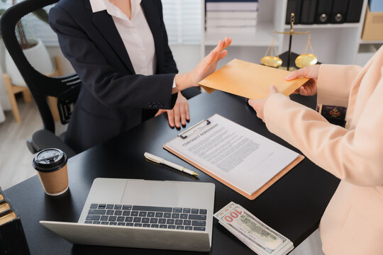 Bribe Refusal: A business person in a suit refuses to accept a bribe envelope, pushing it away from a document on a desk. Emphasizing integrity and ethical choice in a professional setting.