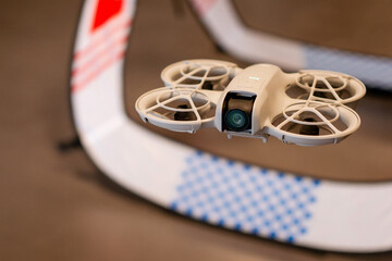 Close up of lightweight palm sized quadcopter with propeller guards flying inside a drone racing arena © MarijaBazarova