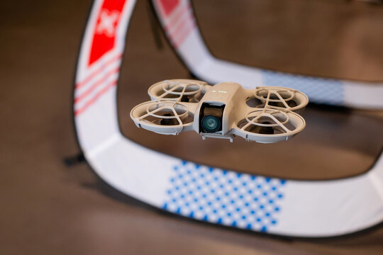 Close up of lightweight palm sized quadcopter with propeller guards flying inside a drone racing arena