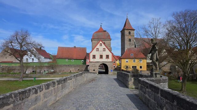 Steinbr&uuml;cke &uuml;ber einen Fluss zu einem Dorf mit einer Kirche und historischen Geb&auml;uden unter blauem Himmel, Fr&uuml;hling, Ornbau, Triesdorf, Fr&auml;nkischen Seenland, Landkreis Ansbach, Mittelfranken, Bayern, 