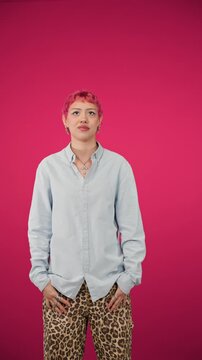 Young stylish person with pink hair posing on magenta background