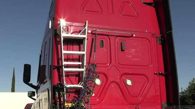 Back of cab of red truck with ladder, air lines, electrical lines.  Slow pan downward.
