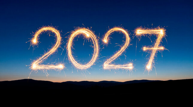 Sparkler light painting 2027 numbers against twilight sky over mountain landscape silhouette