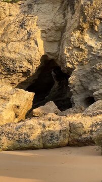 Warm side light gradually reveals a star-like opening leading inside the coastal cliffs during slow camera movement along the rocky shoreline.