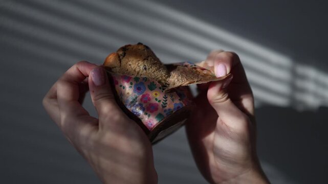 Female hands carefully unwrap freshly baked easter bread from baking paper revealing a traditional homemade holiday pastry ready for decoration