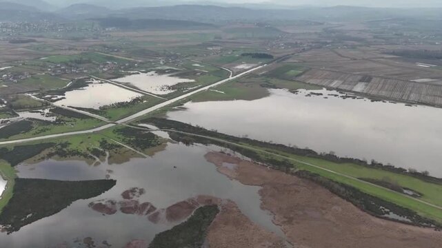 Aerial view of Kizilirmak Delta featuring vast wetlands, irrigation canals, and agricultural fields under a cloudy sky in Bafra, Samsun, Turkiye.