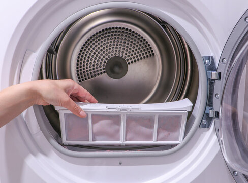 Clothes Dryer with Stainless Steel Tub, Front Load Tumble. Compact Drying Unit for Laundry, Apartments, Dorms. female hand taking lint out of dirty air filter of dryer machine. High quality photo