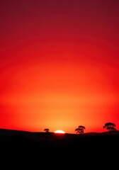 Fototapeta premium Intense red and orange hues paint the dramatic morning sky above the silhouette of the peaceful landscape at dawn, breaking light, peaceful, atmosphere